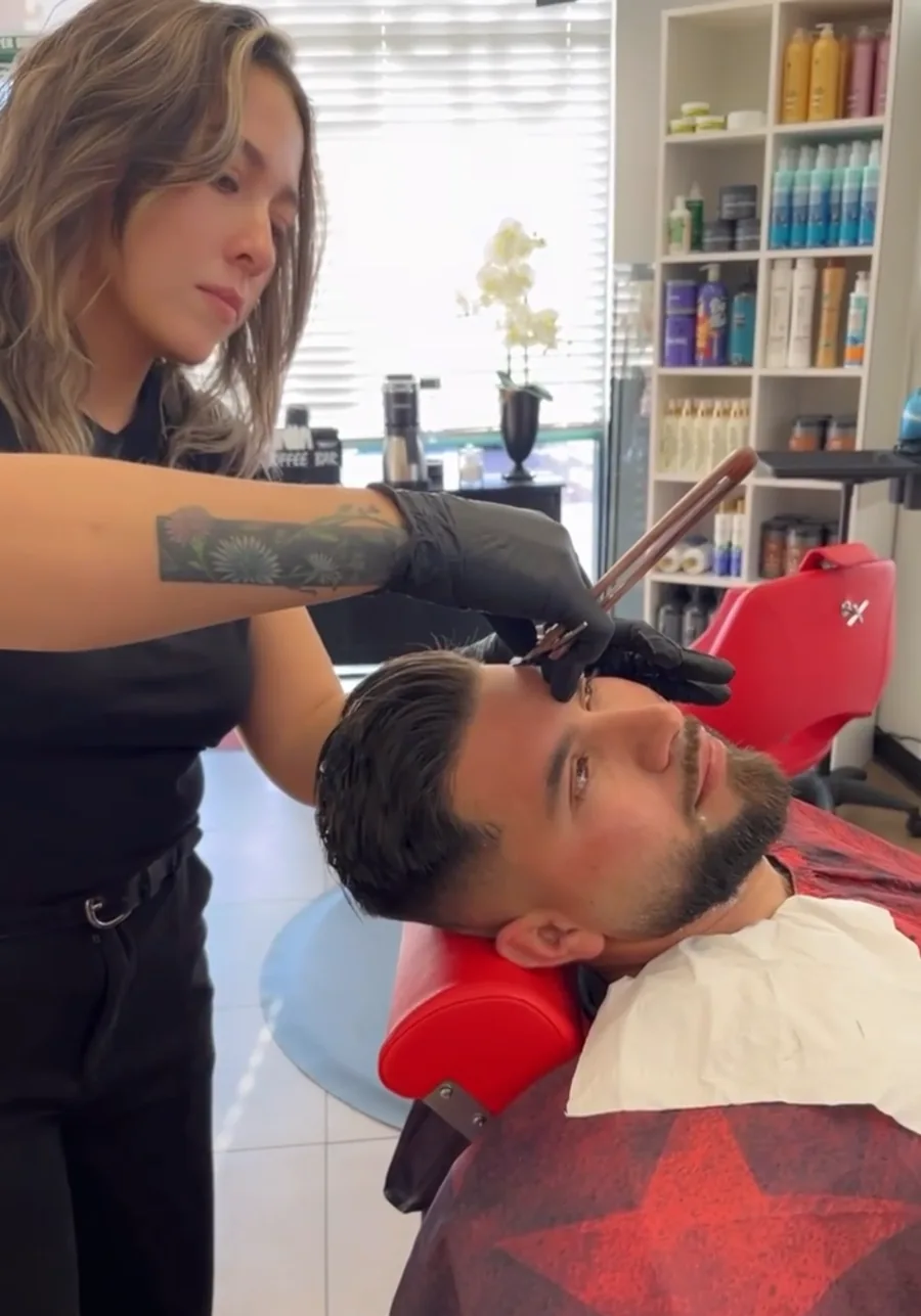 Yasmin detailing a client's brow line with a straight razor