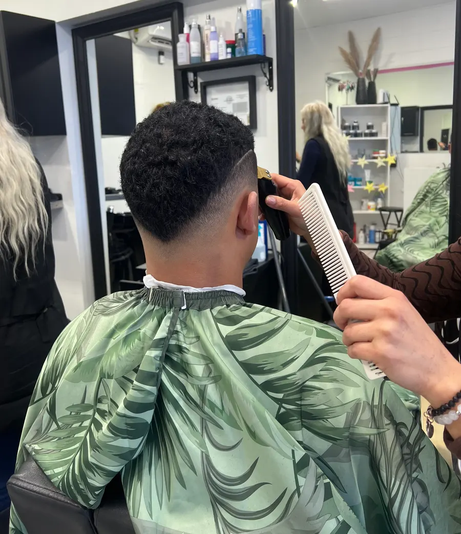 A curly top fade being blended clean at the chair