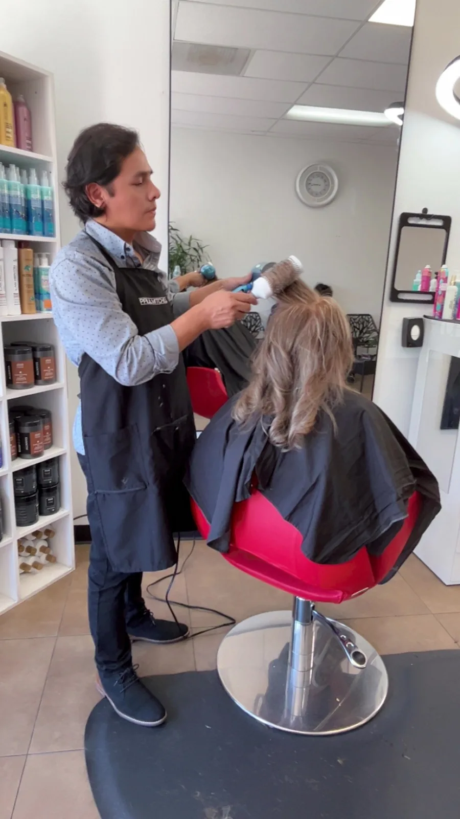 Jorge blow drying and finishing a client inside the salon